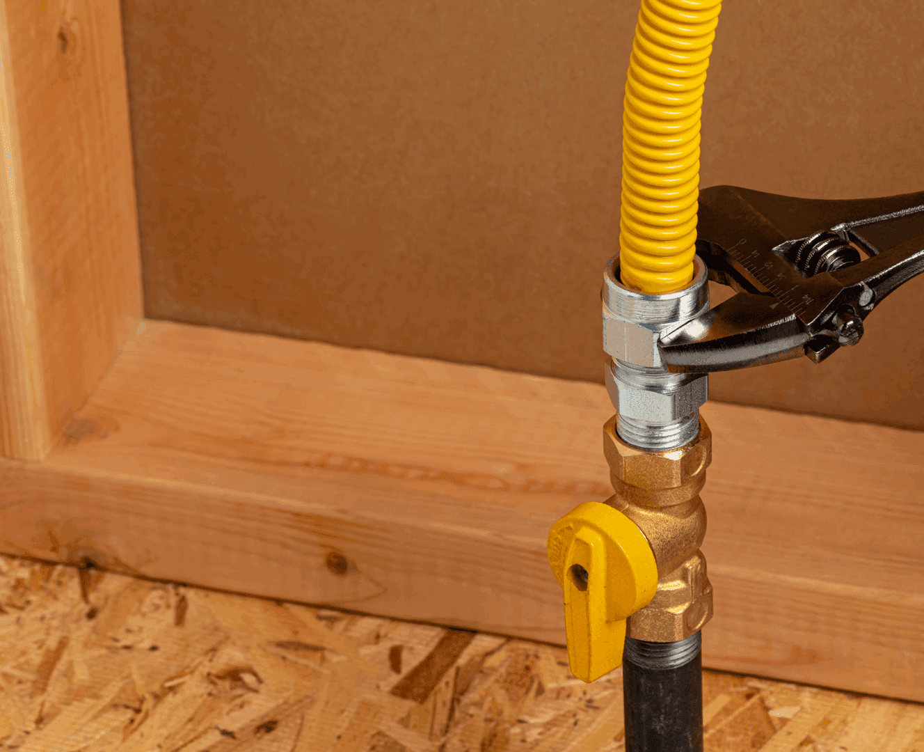 Wrench tightening yellow gas pipe fitting.